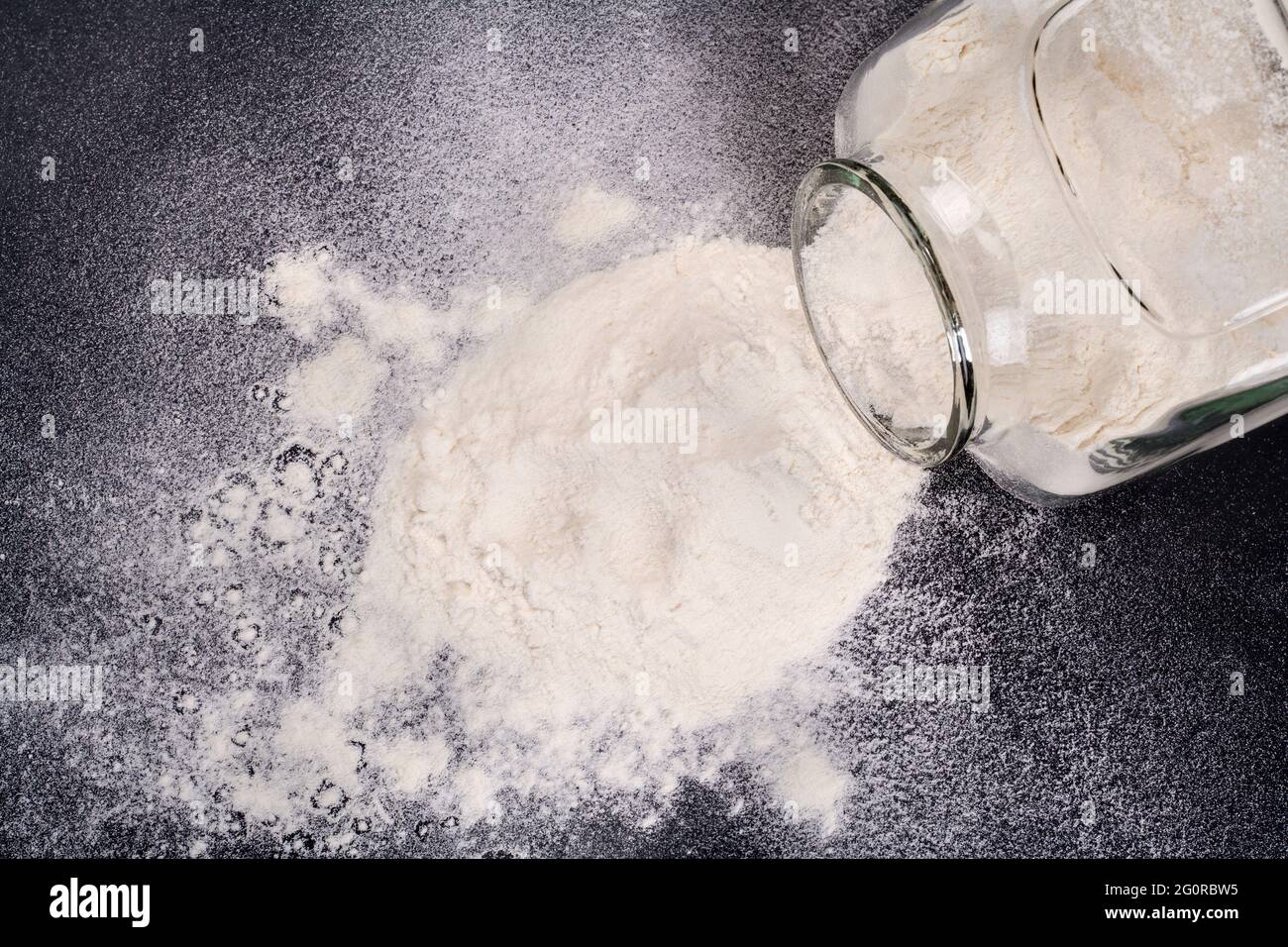 Glass jar with flour spilled on black Stock Photo Alamy