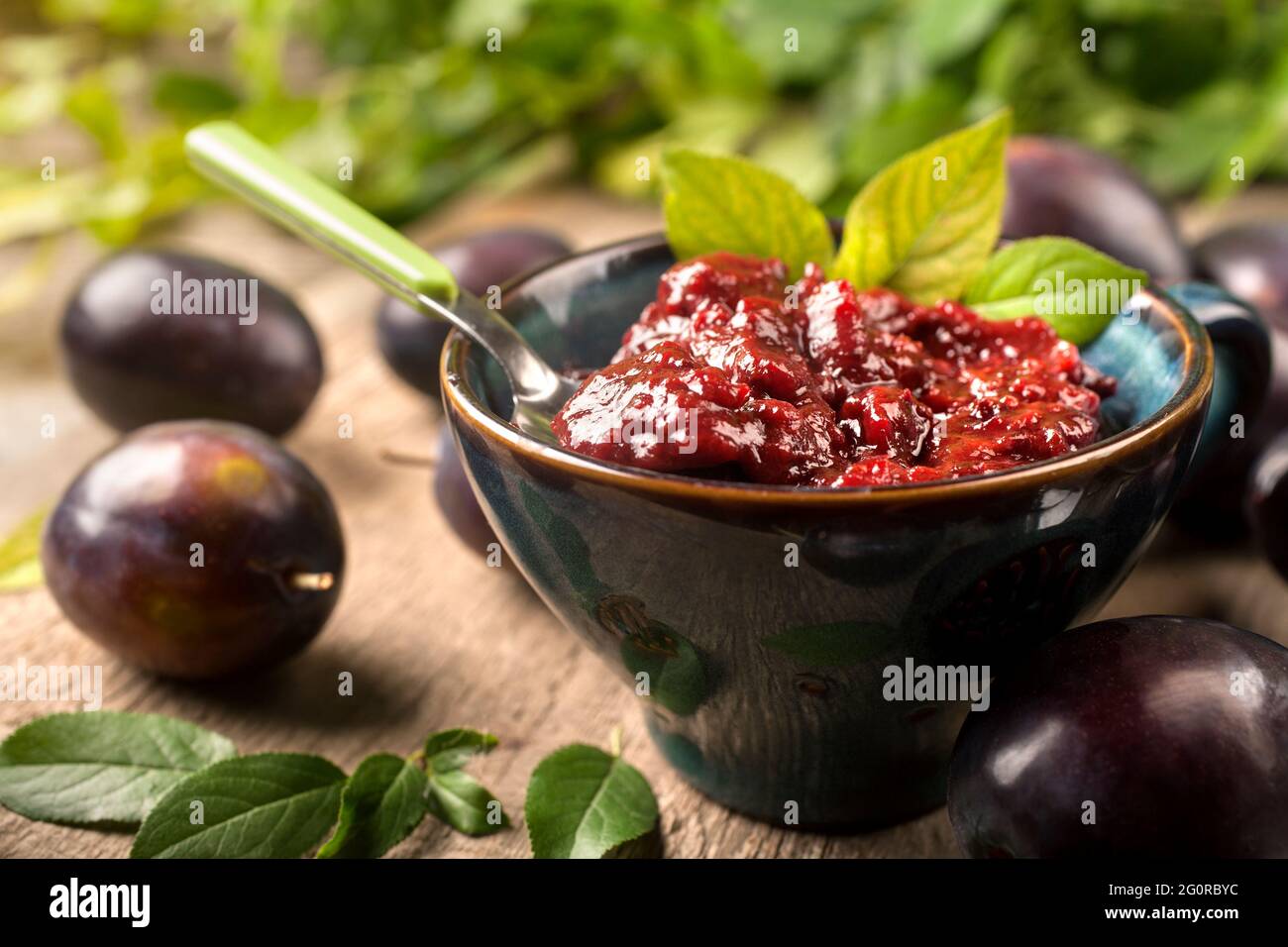 Jam of healthy organically grown plums with plum fruits on a wooden table background Stock Photo