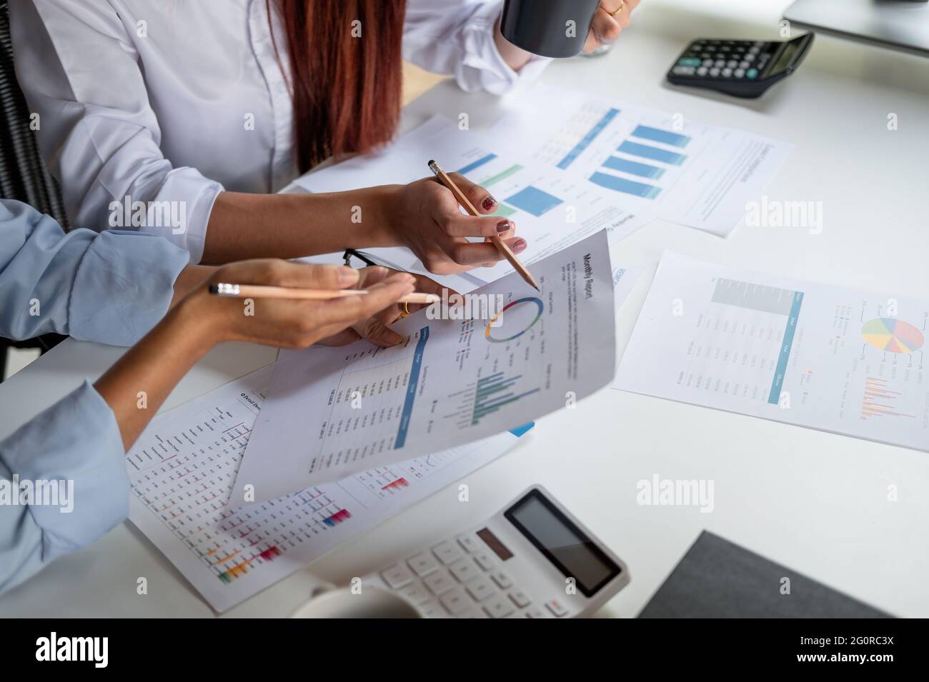 Two colleagues discussing with document data and calculator on desk table. Close up business team analysis and strategy concept Stock Photo
