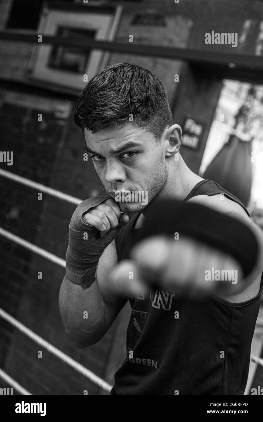 Young athletic man preparing for boxing competitions, training defense and attacks in boxing club. Stock Photo