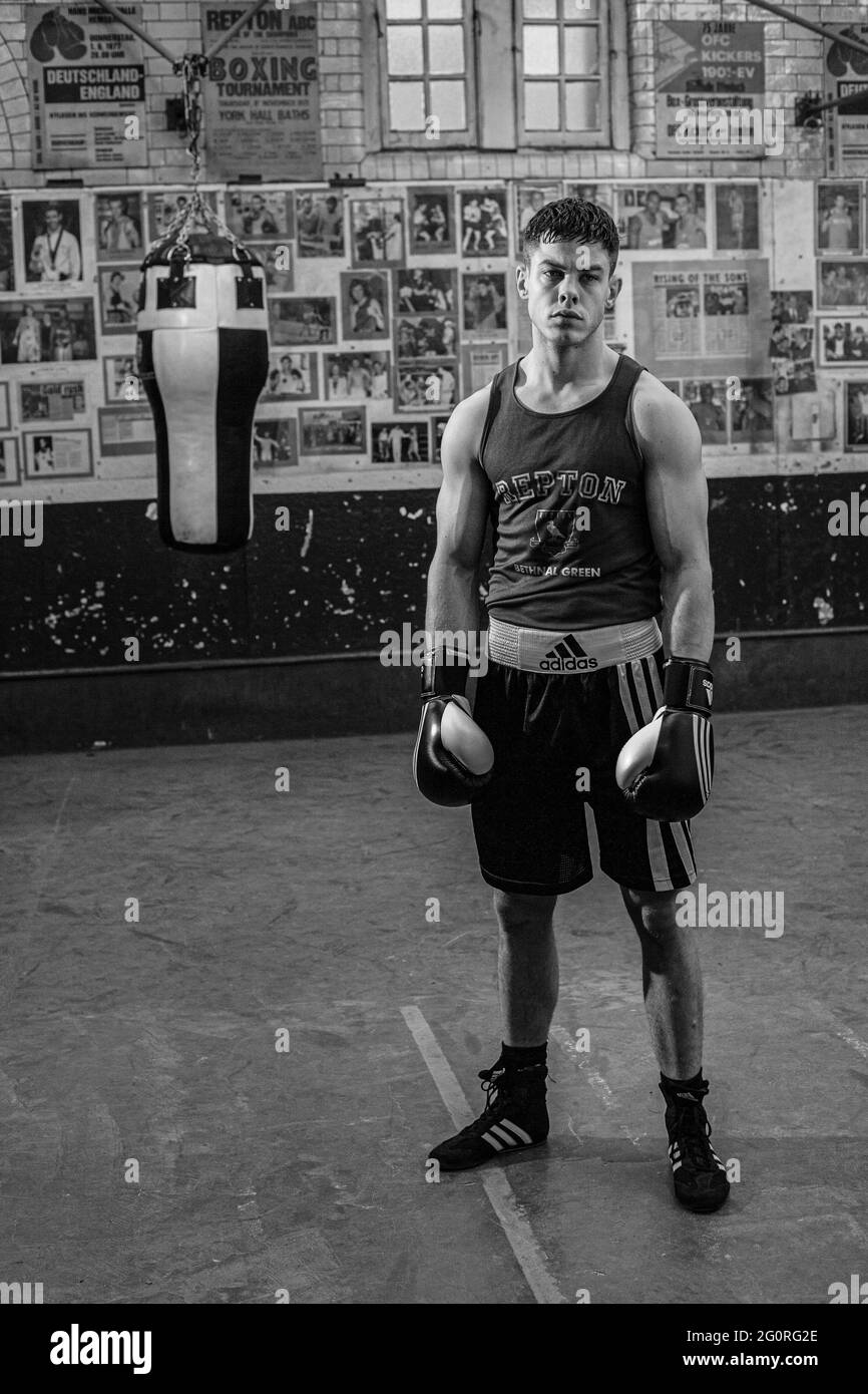 Handsome boxer standing in front of punching bag in gym Stock Photo