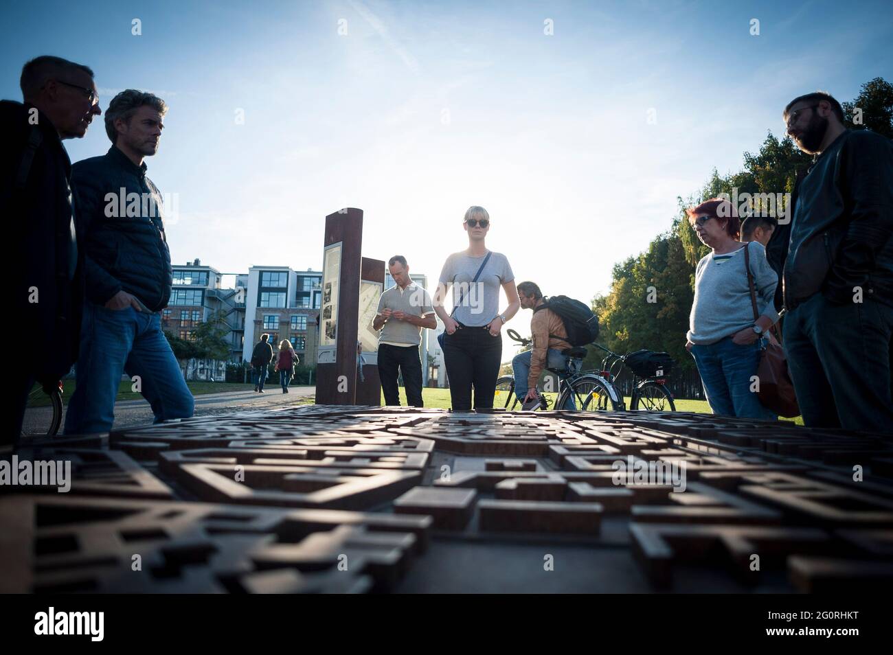 A woman stands in a park in Berlin, Germany looking at a 3D map of the area and seeing where the Berlin Wall divided the city. Stock Photo