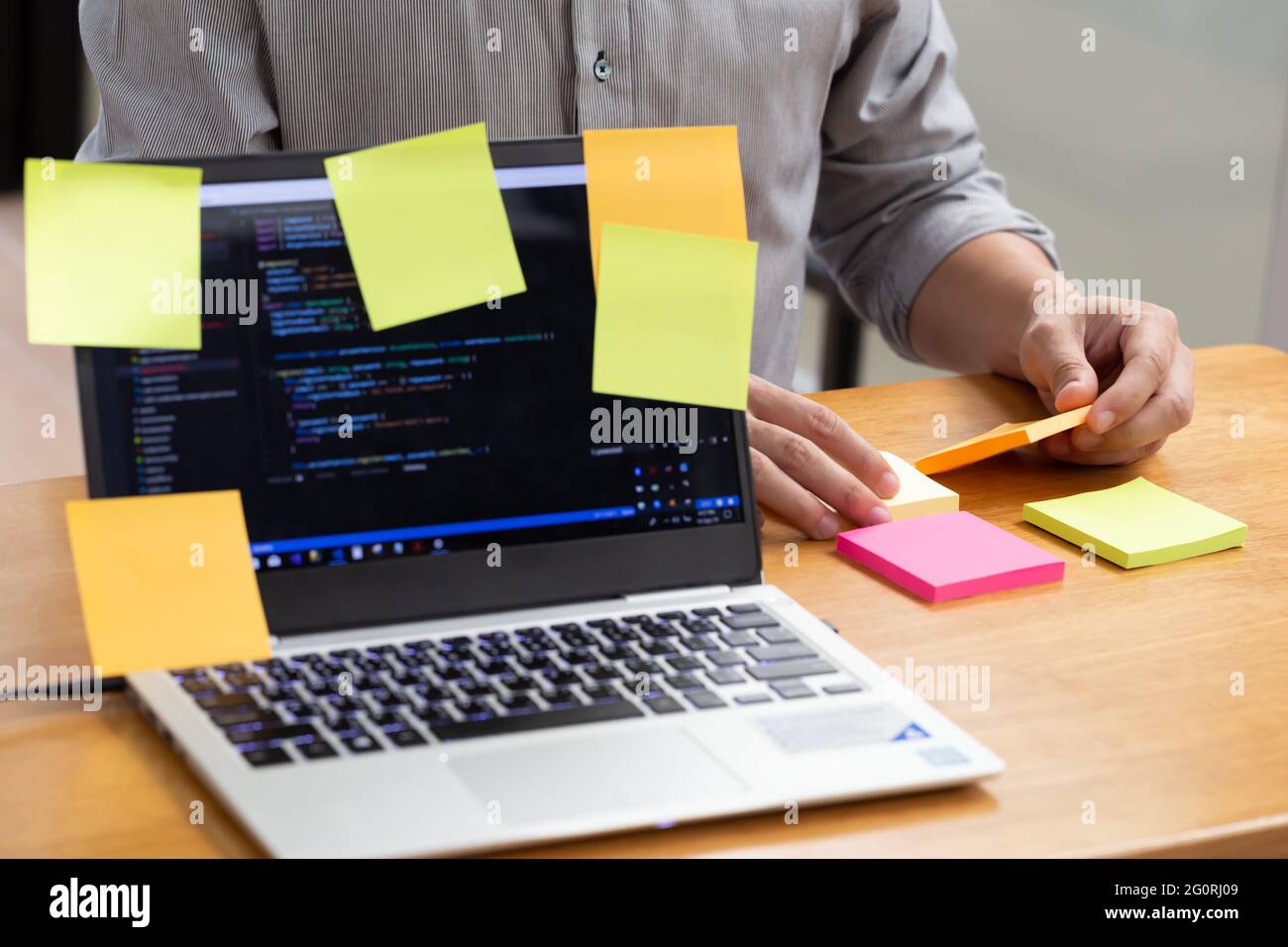 Tasks on sticky note cards on laptop computer with source code program