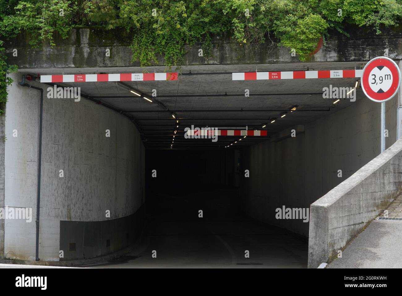 Entrance to a underground parking lot. There is height limit 3.9 m sign for vehicles. Stock Photo