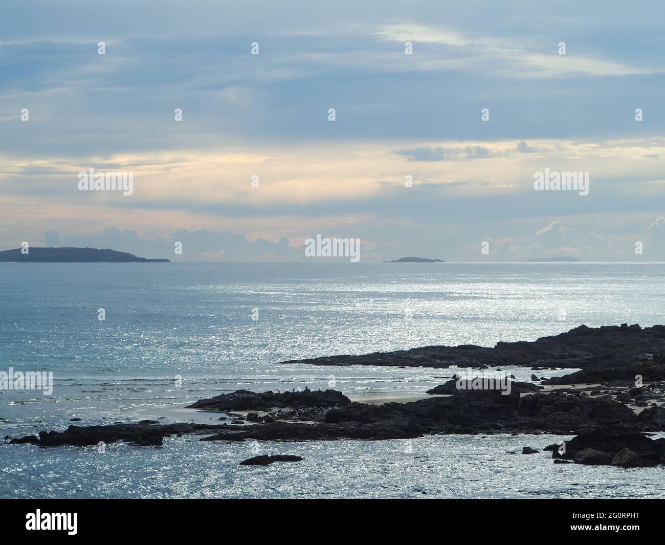 the shimmering blue Pacific Ocean in front of a beautiful cloudy ...