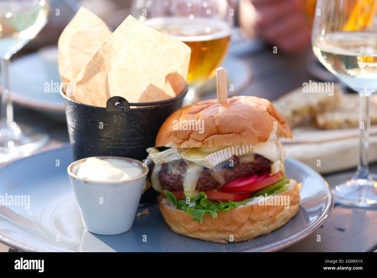 Group of friends toasting beer and wine glasses and eating burgers in