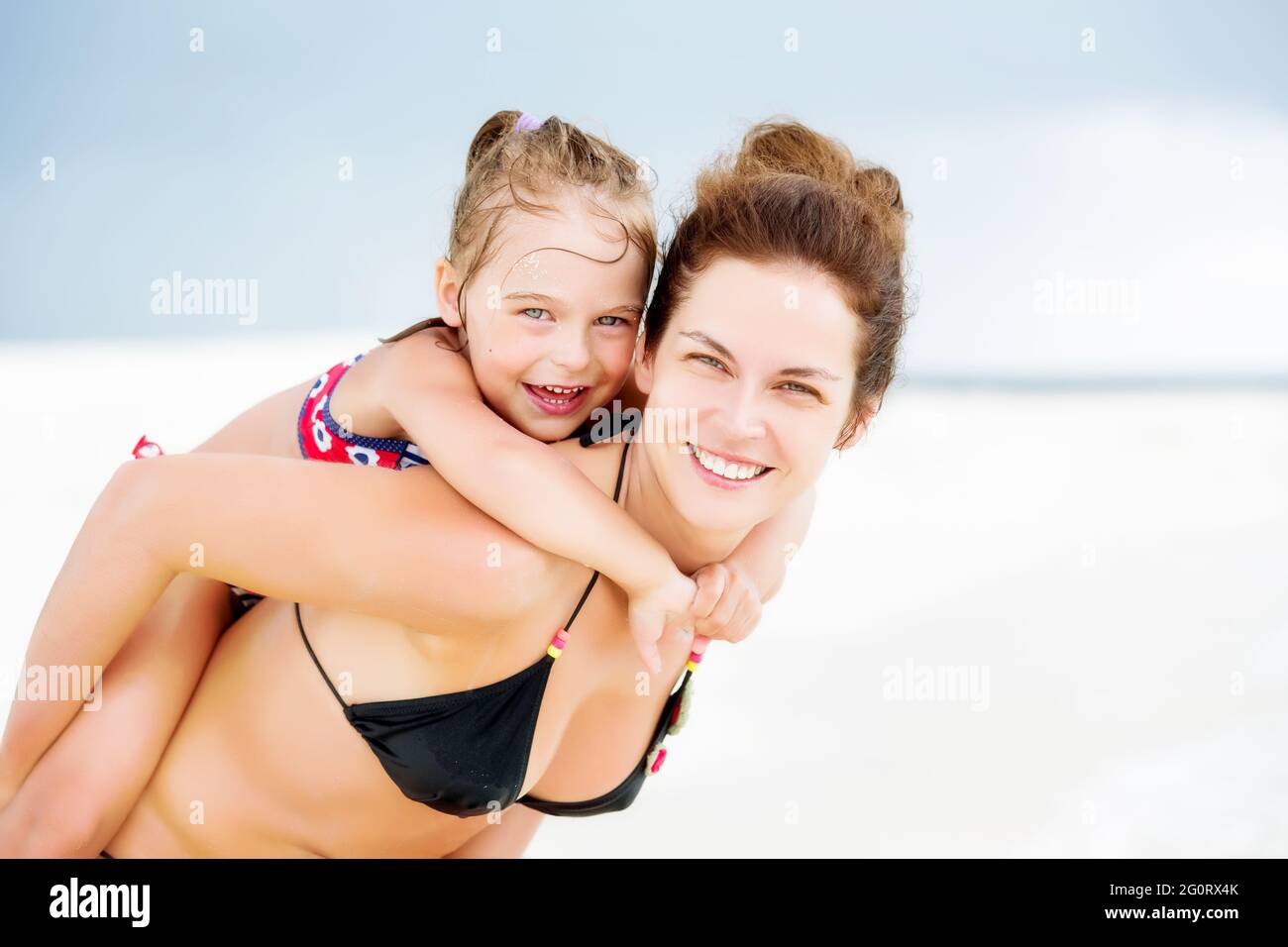 Happy mother and little daughter having fun on sand beach on Maldives at summer vacation. Family on the beach concept. Stock Photo