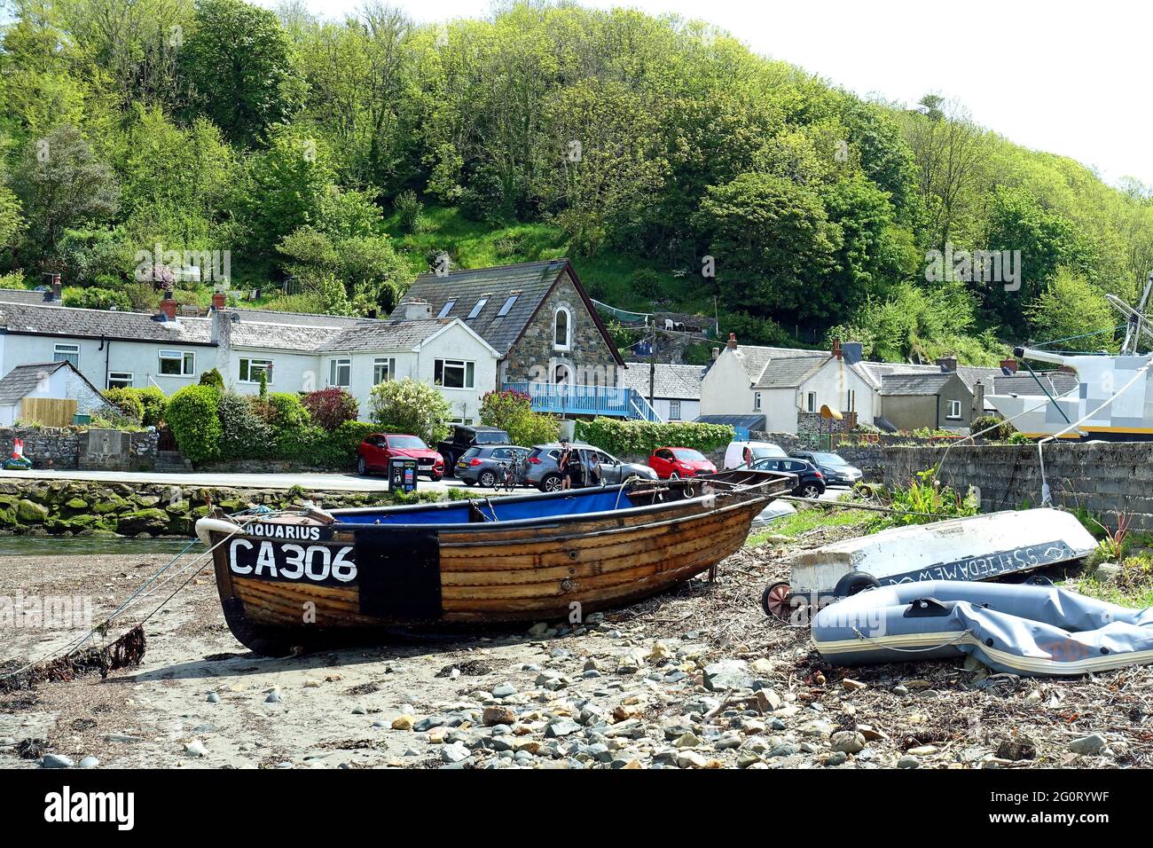 Traditional wooden fishing boat and dinghies on the tideline at Fishguard Lower Harbour, Pembrokeshire, Wales Stock Photo