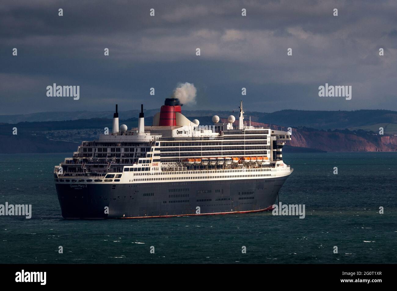 The magnificent Queen Mary 2 ocean liner cruise ship sits on choppy seas whilst anchored off Torbay in Devon, UK. Stock Photo