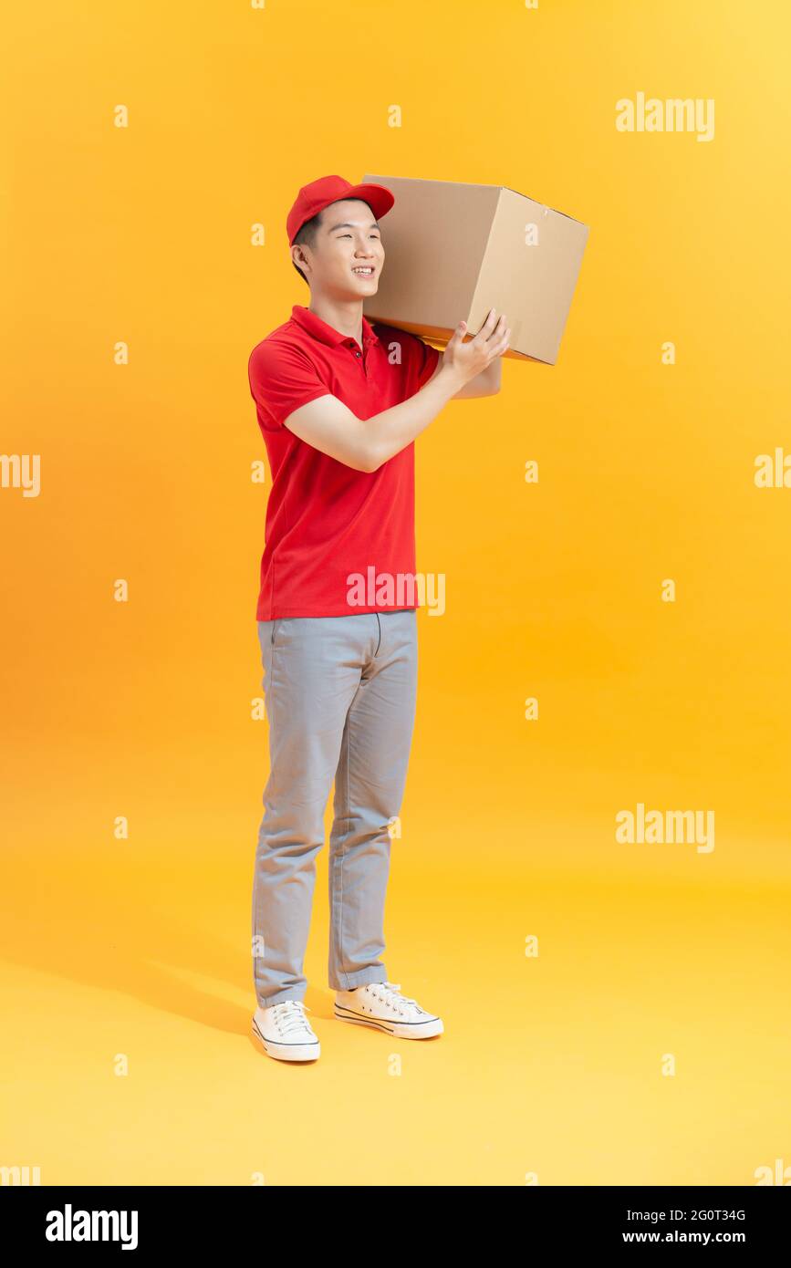 happy young delivery man in red cap standing with parcel post box ...