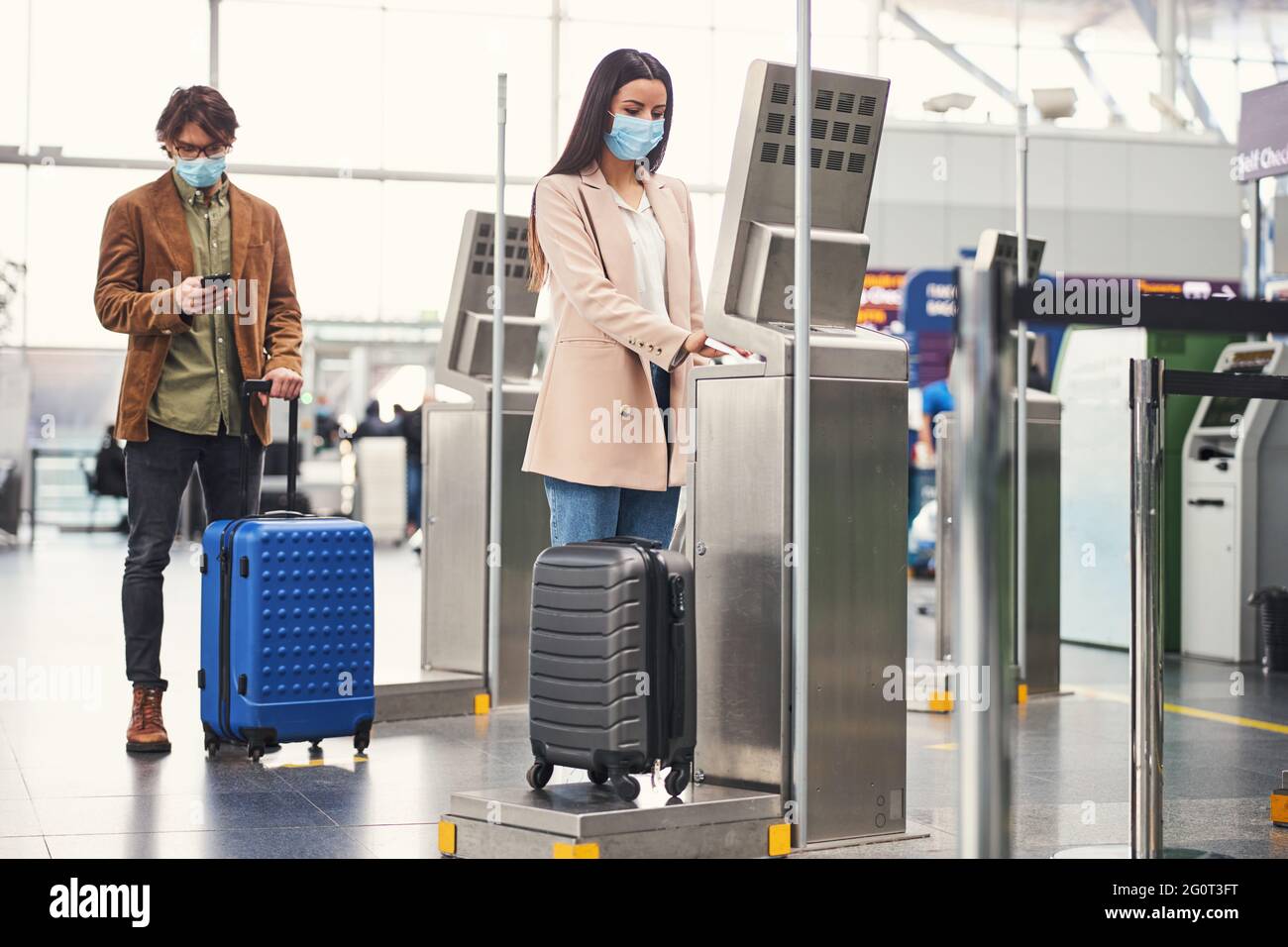 Passengers using baggage check weighing machine at airport Stock Photo