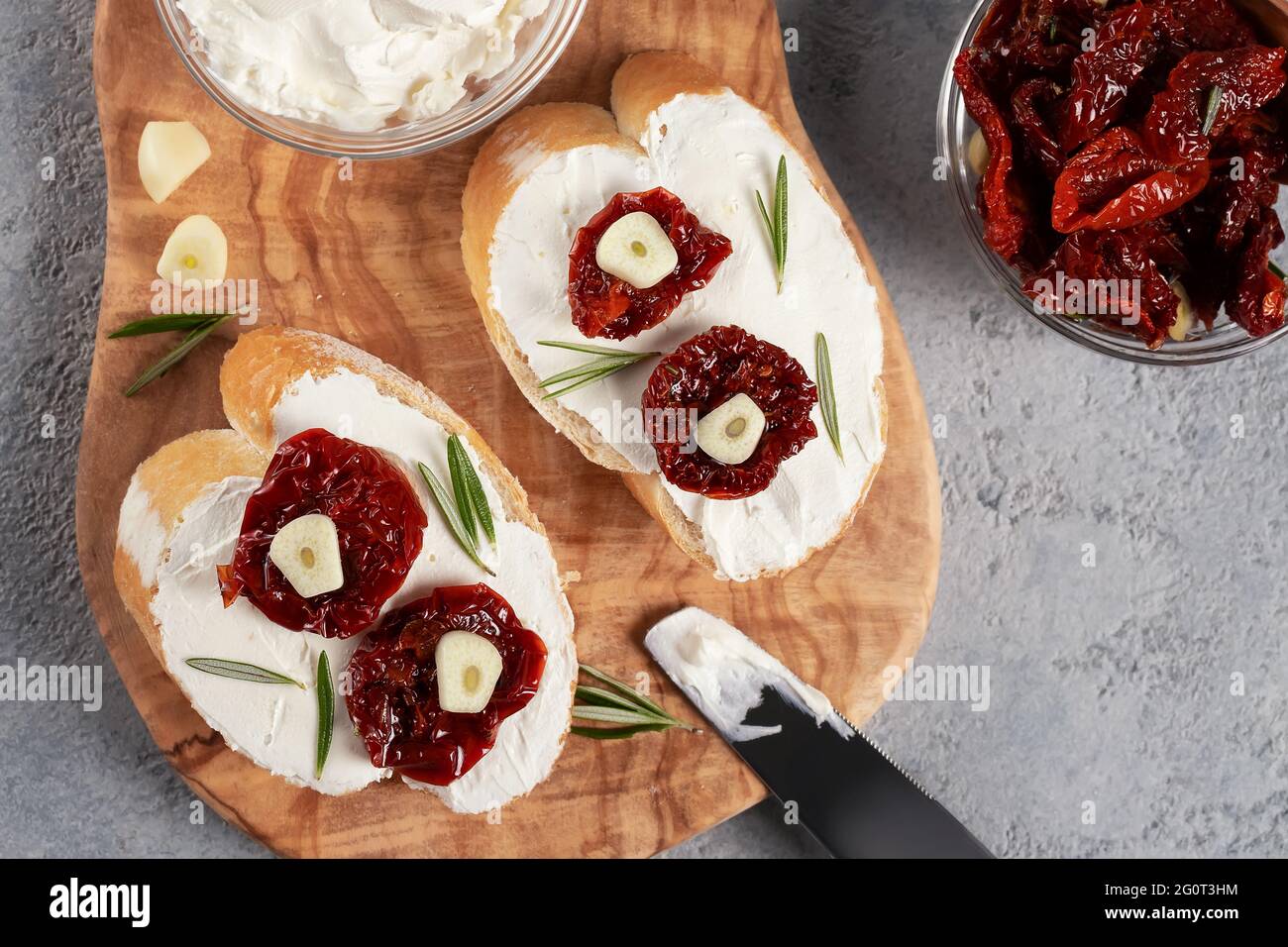 Homemade sandwiches with cream cheese and sun-dried tomatoes on a wooden board of olive - delicious healthy breakfast, italian cuisine, flat lay. Stock Photo