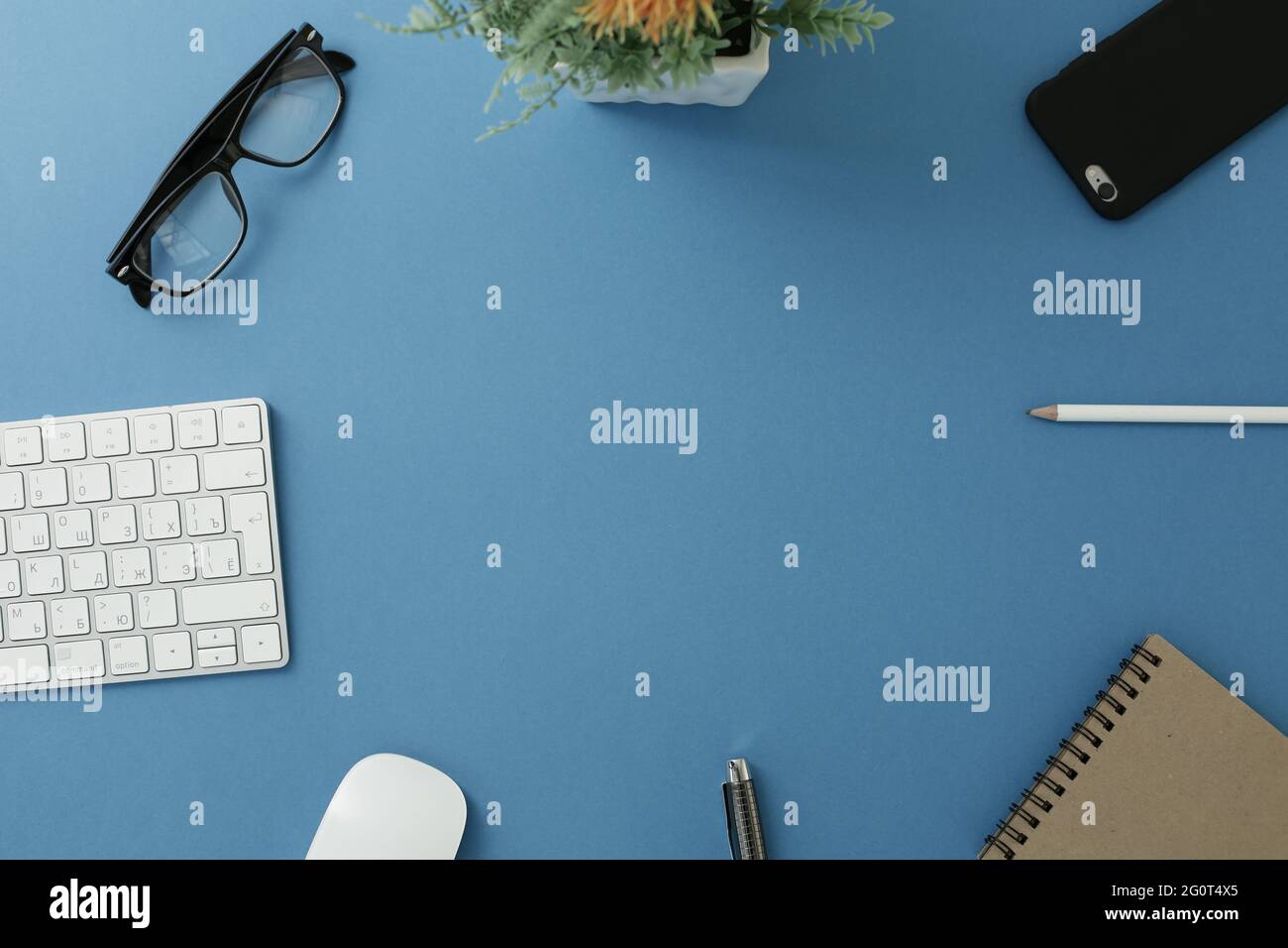 Glasses keyboard flower notepad mouse pen pencil and phone on blue background Stock Photo