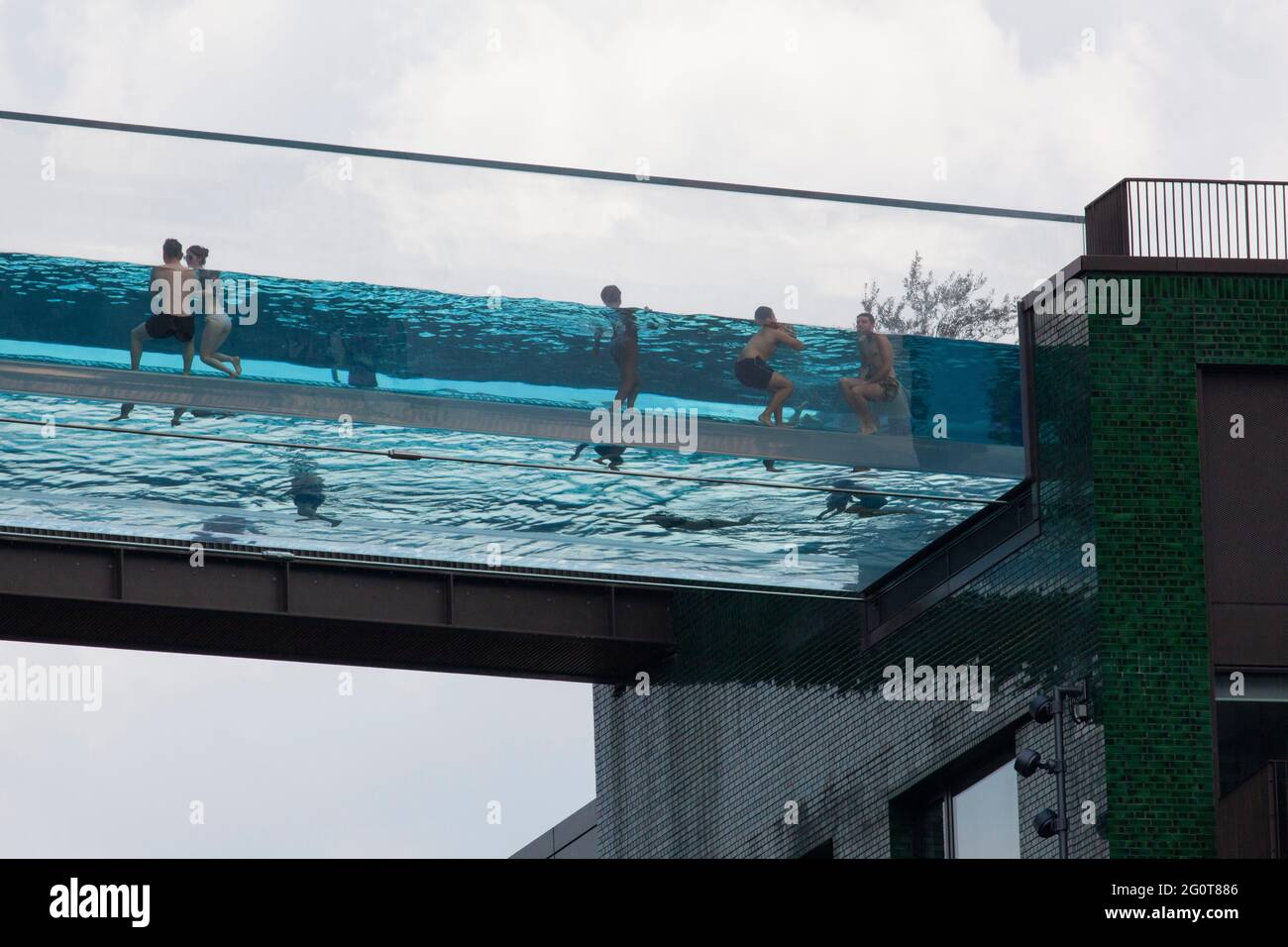 London, UK, 2 June 2021: At Embassy Gardens, in the Nine Elms area around the American Embassy, residents of luxury apartments have access to the Sky Pool, 115 feet above the ground. Linking two buildings with a completely clear structure, swimmers may have an air of exclusivity as a two-bedroom apartment costs over £1 million, but they have no privacy. Anna Watson/Alamy Stock Photo