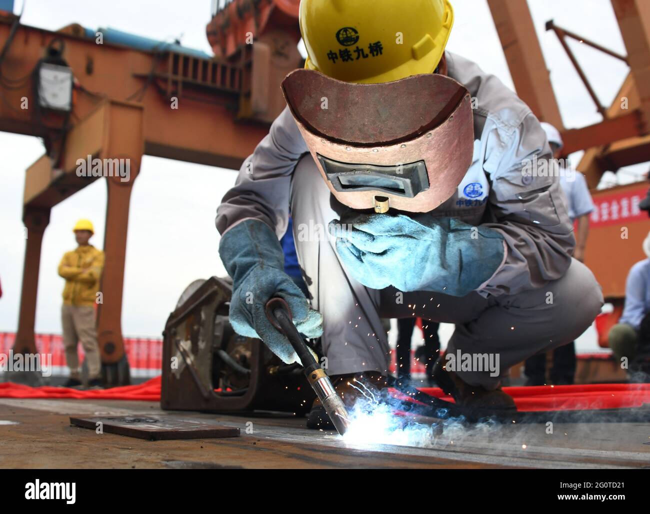 (210603) -- WUHAN, June 3, 2021 (Xinhua) -- A worker welds the last part of the steel girder at the closure segment of Bianyuzhou Yangtze River Bridge on the border of central China's Hubei Province and east China's Jiangxi Province, June 3, 2021. Connecting Huangmei County of central China's Hubei Province and Jiujiang City of east China's Jiangxi Province, the bridge is part of Anqing-Jiujiang Railway. The railway has a designed speed of 350 kilometers per hour for the two high speed lines and 200 kilometers per hour for the other two reserved passenger and freight lines. (Xinhua/Cheng Min) Stock Photo