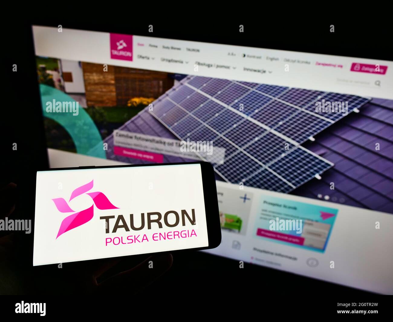 Person holding cellphone with logo of Polish energy company Tauron Polska Energia SA on screen in front of business webpage. Focus on phone display. Stock Photo