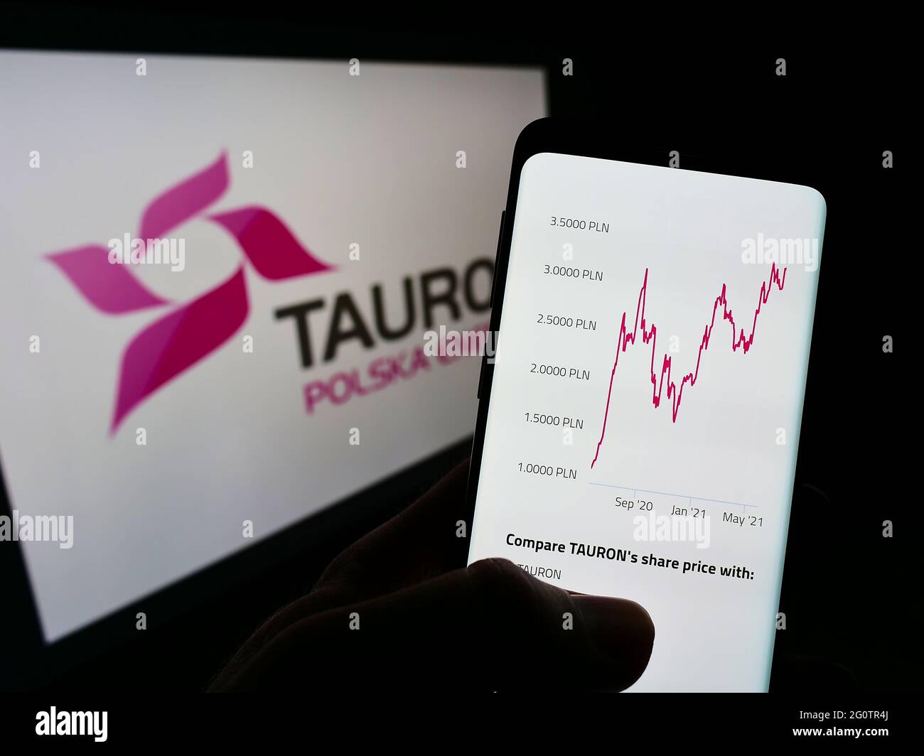Person holding mobile phone with webpage of Polish energy company Tauron Polska Energia SA on screen with logo. Focus on center of phone display. Stock Photo