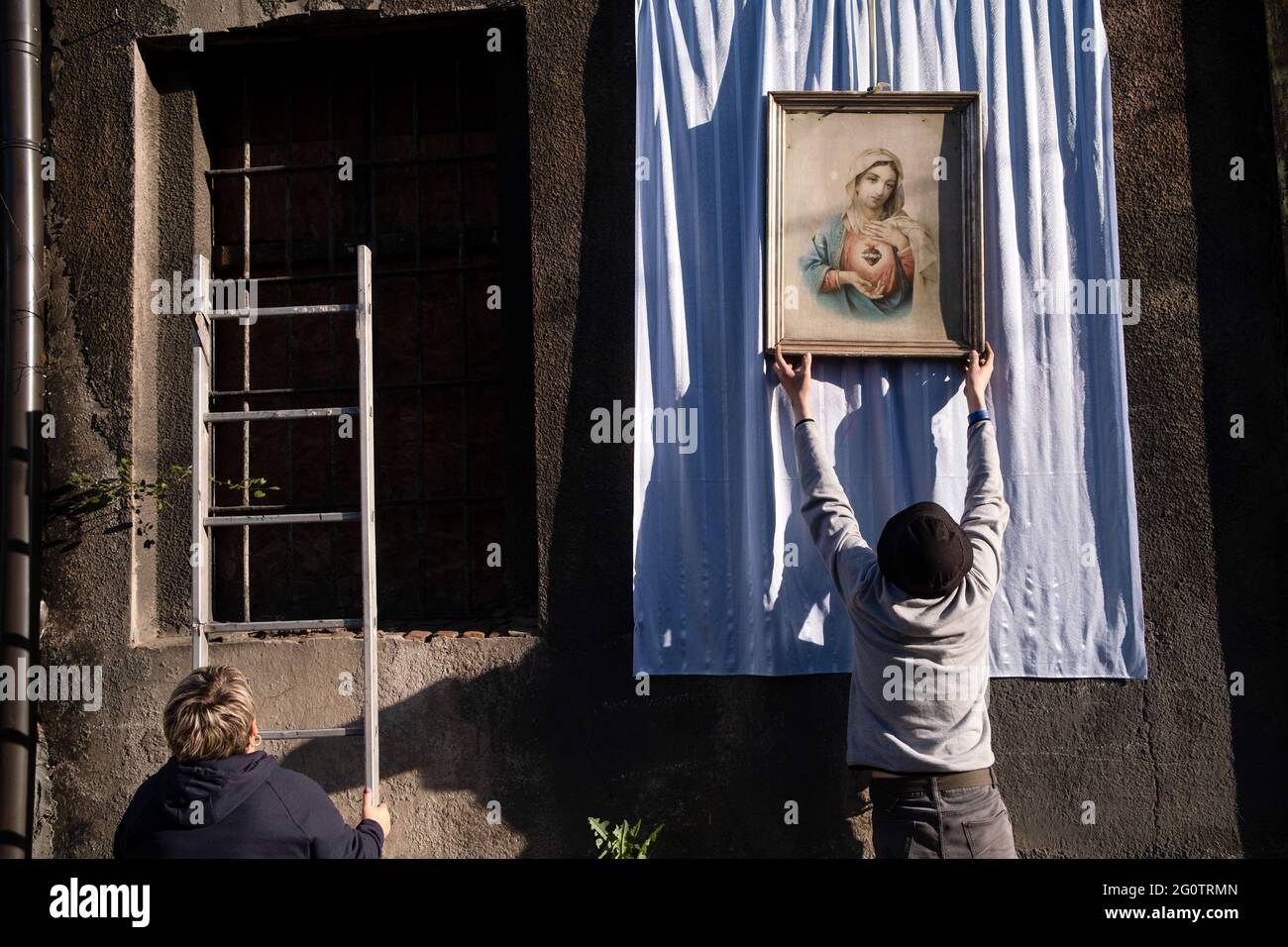 Swietochlowice, Lipiny, Poland. 03rd June, 2021. A man seen hanging the holly picture on the wall of the building during the procession. Corpus Christi (Boze Cialo) it is a traditional feast celebrated in the Catholic Church. From the early morning hours, residents of the Lipiny- district in Swietochlowice, Silesia, decorate their streets and build altars. They are waiting for the procession of the faithful in traditional costumes which goes around the streets. The priest with the monstrance goes with them too. Credit: SOPA Images Limited/Alamy Live News Stock Photo