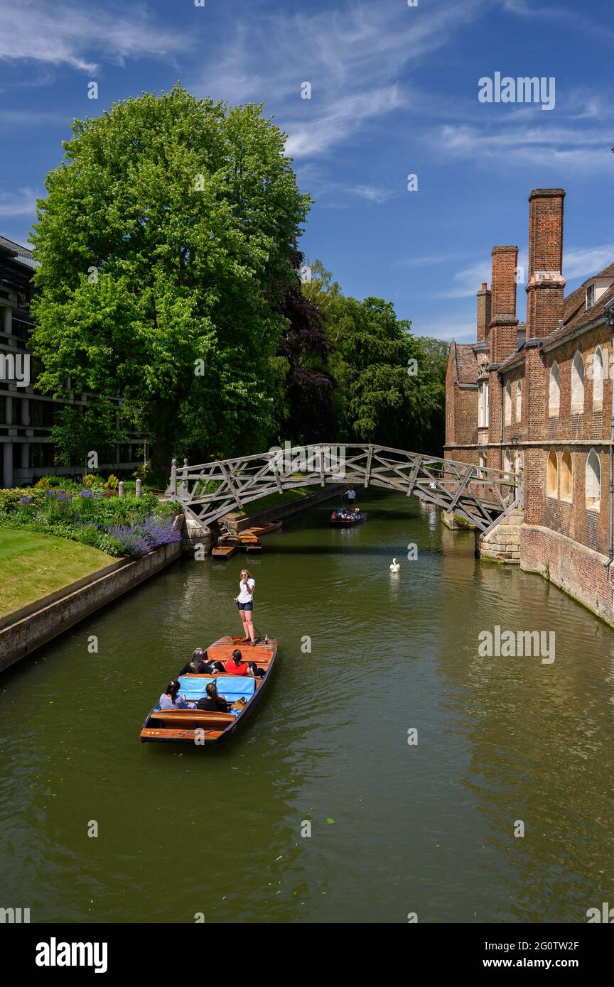 Punting on the River Cam near the Mathematical Bridge behind Queen's College Cambridge, with a vivid blue sky and wispy cirrus clouds Stock Photo