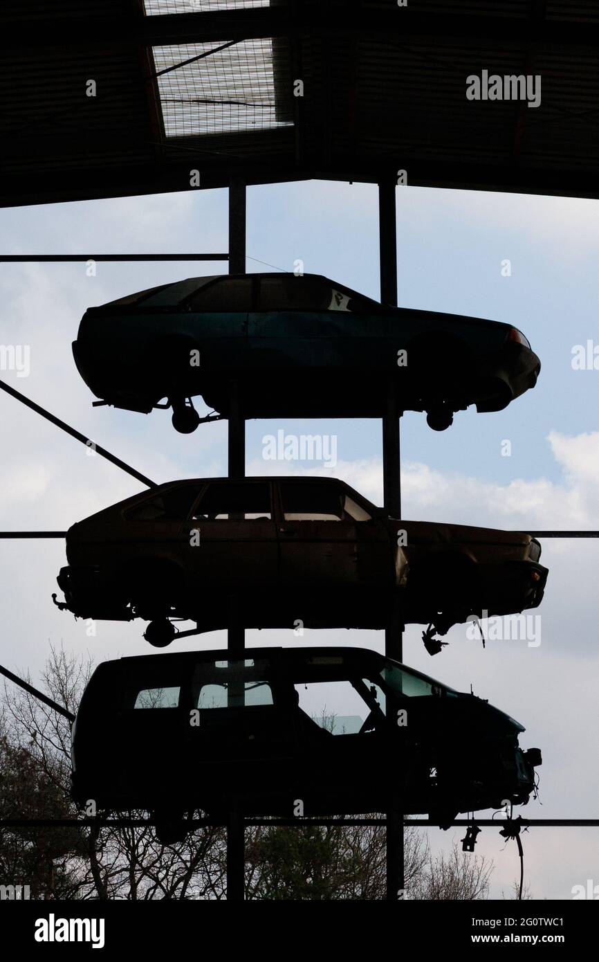 Silhouette of three scrap cars in the high-bay warehouse against a blue ...
