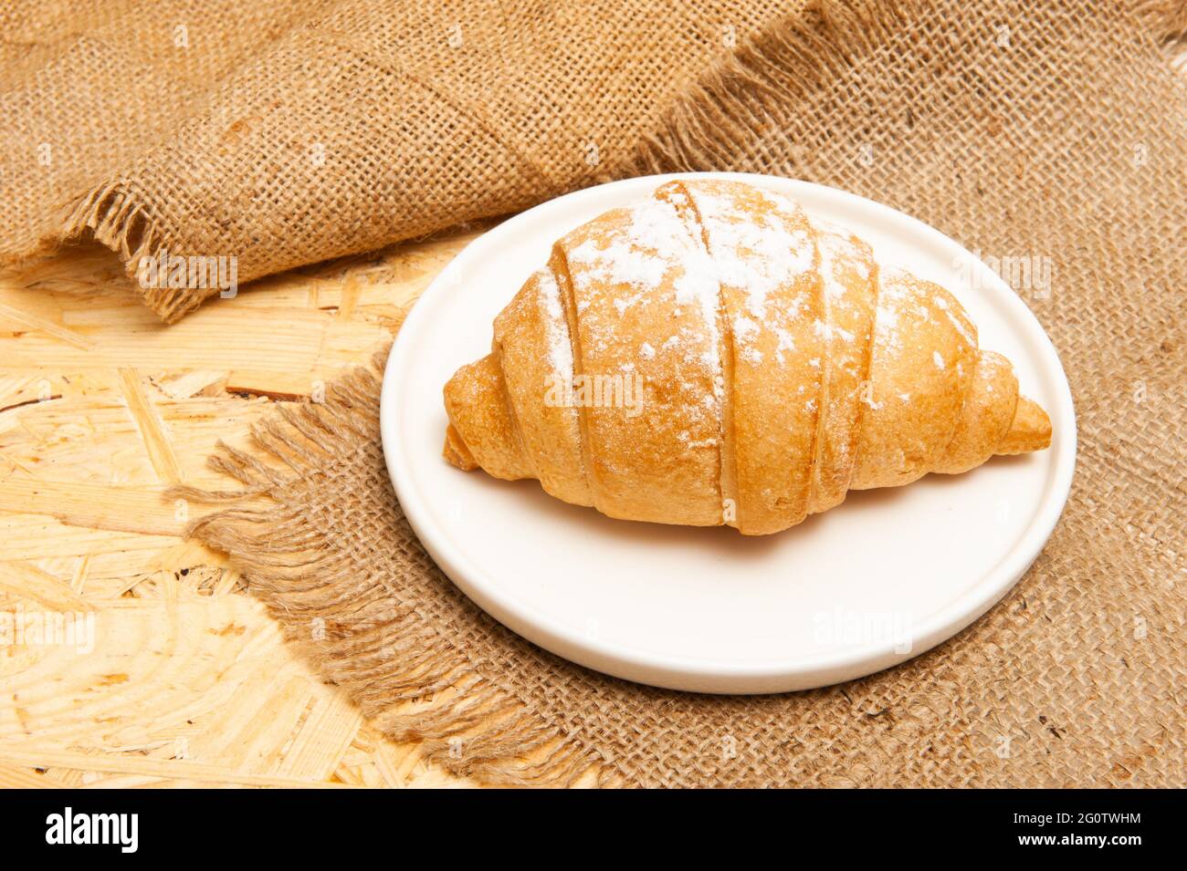 Croissant on a saucer and on a canvas napkin. Top view Stock Photo
