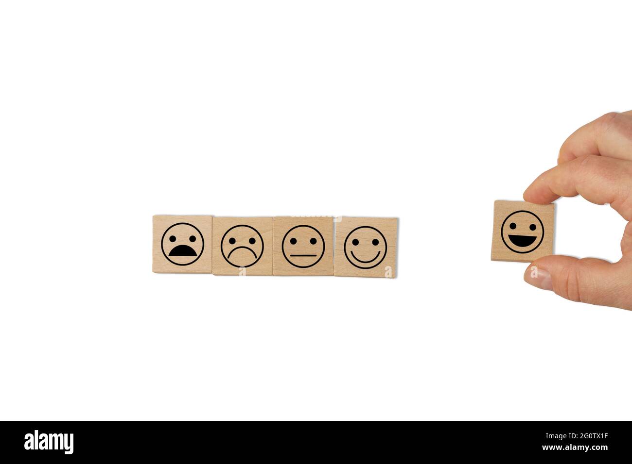 A hand holding a cube with a "happy smilie" symbol, with 4 cubes on the side symbolizing the entire customer satisfaction scale. Stock Photo