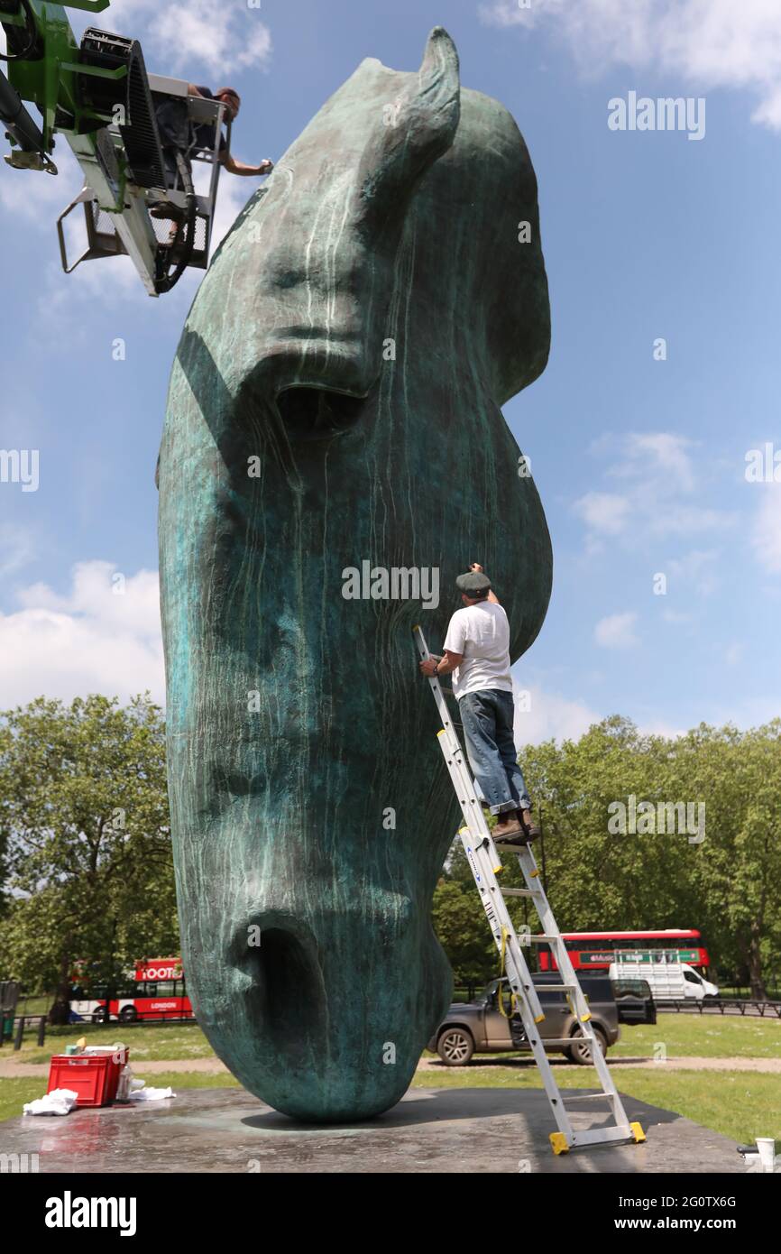 Artist Nic Fiddian-Green uses a ladder, whilst colleague Dan Morphy uses a cherry-picker, to re-paint and wax his 33 ft high bronze sculpture of a horse's head titled Still Water, on display at Achilles Way in Mayfair, London. Picture date: Thursday June 3, 2021. Stock Photo