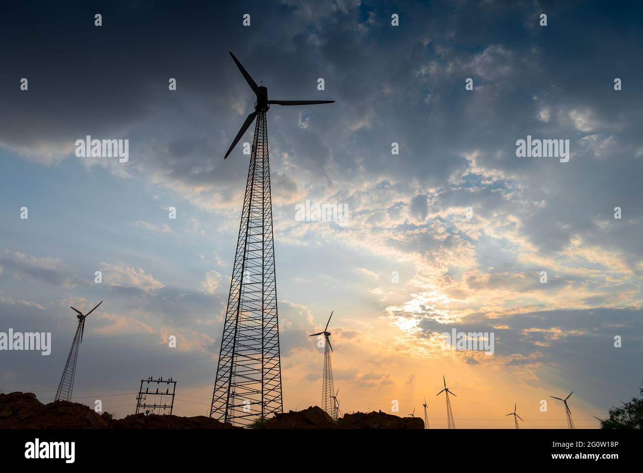 Silhouette of wind mills in twilight with a setting sun and cloudy sky in background, Rajasthan, India Stock Photo