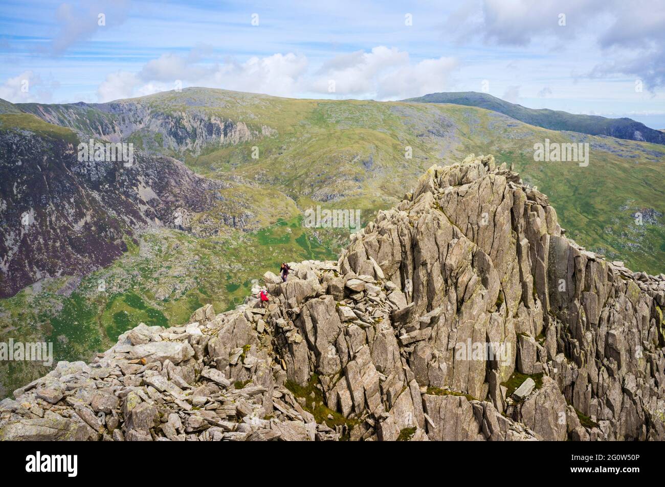 View to Tryfan with hikers scrambling on rocky north ridge in mountains of Snowdonia National Park. Ogwen, Conwy. North Wales, UK, Britain Stock Photo