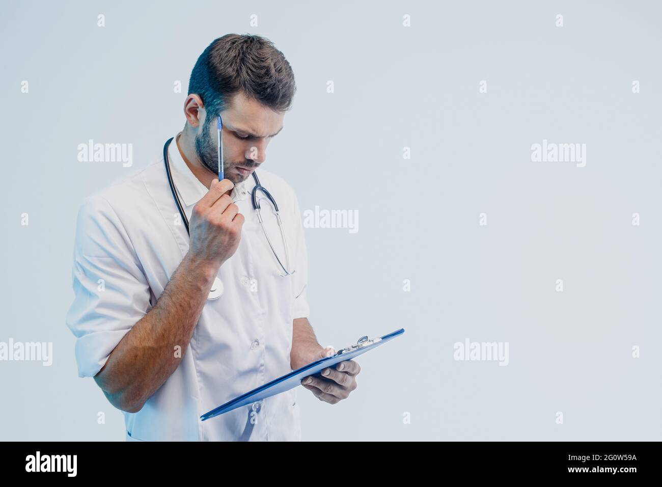 Thoughtful male doctor read something in clipboard Stock Photo