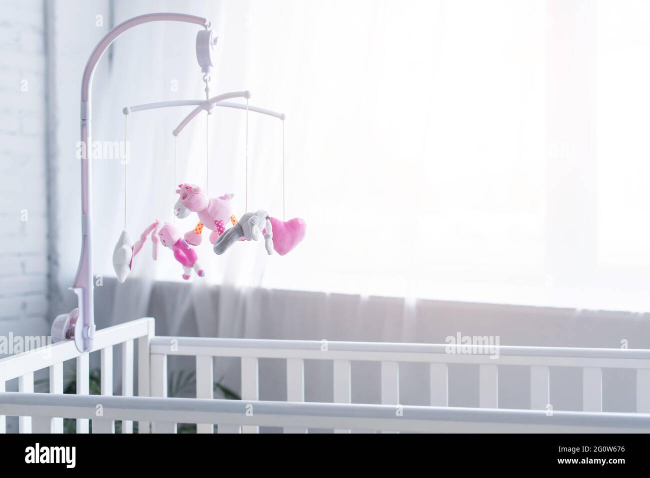 soft toys hanging over crib in nursery near window Stock Photo Alamy