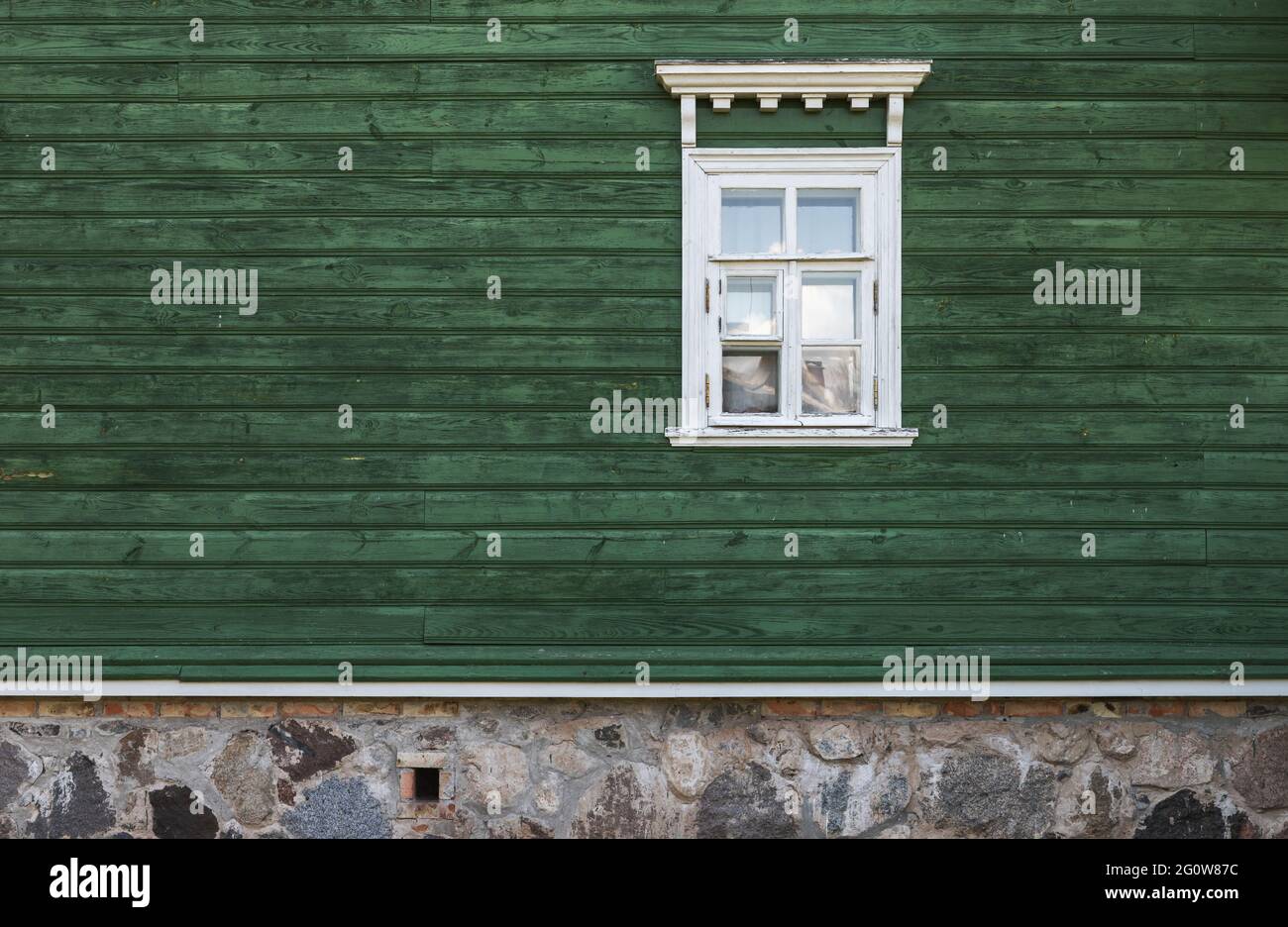 Window with white decorative frame in an old green wooden wall, architectural background texture Stock Photo