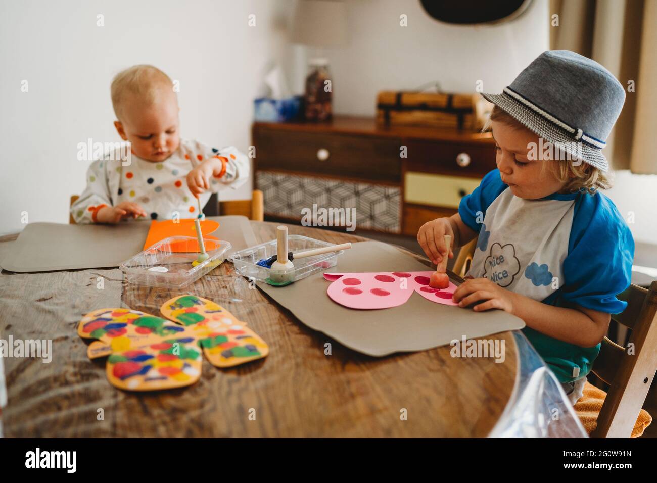 Young children painting butterflies at home being creative and messy Stock Photo