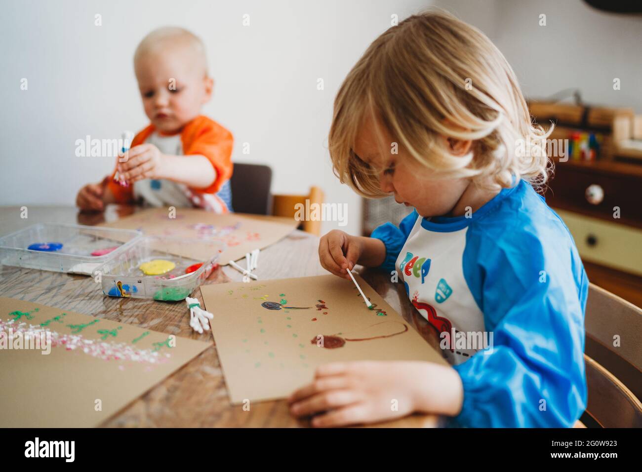 Young kids painting with lots of colorful paints at home in lockdown Stock Photo