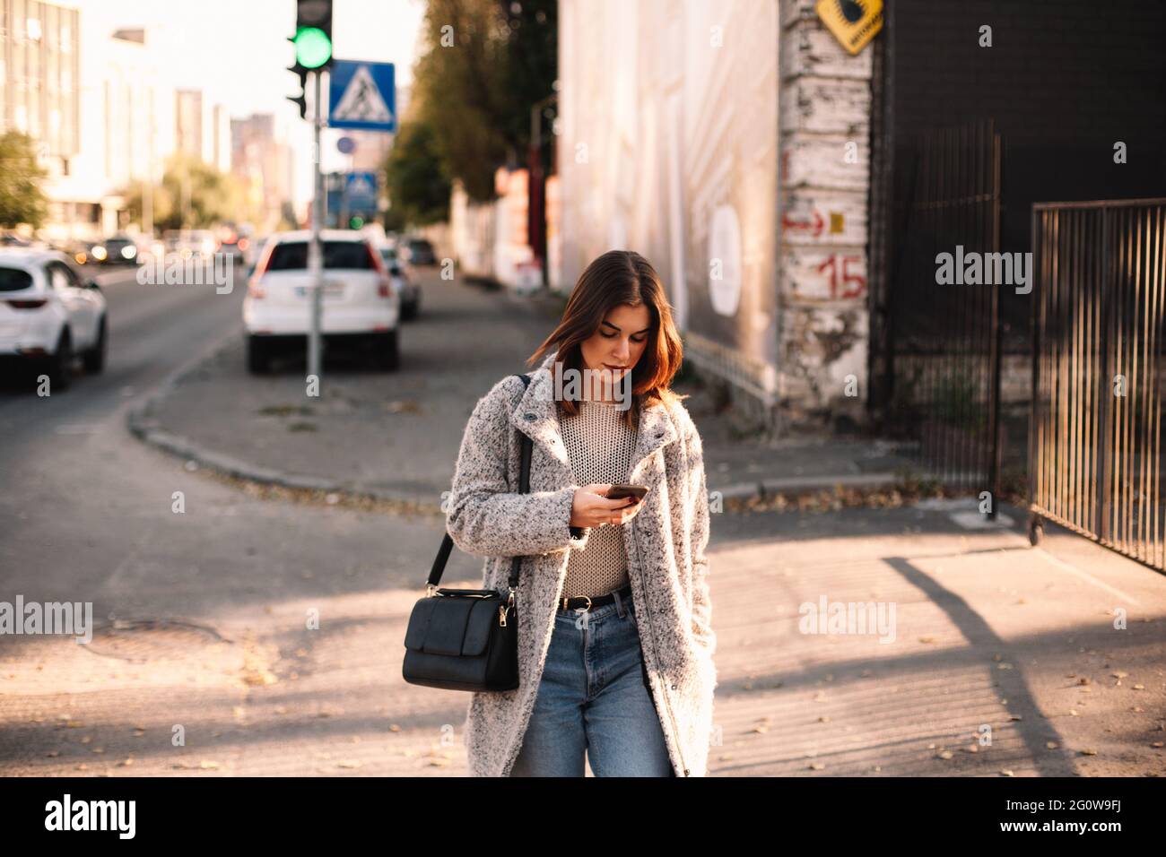 Non-binary woman using smart phone while walking in city Stock Photo
