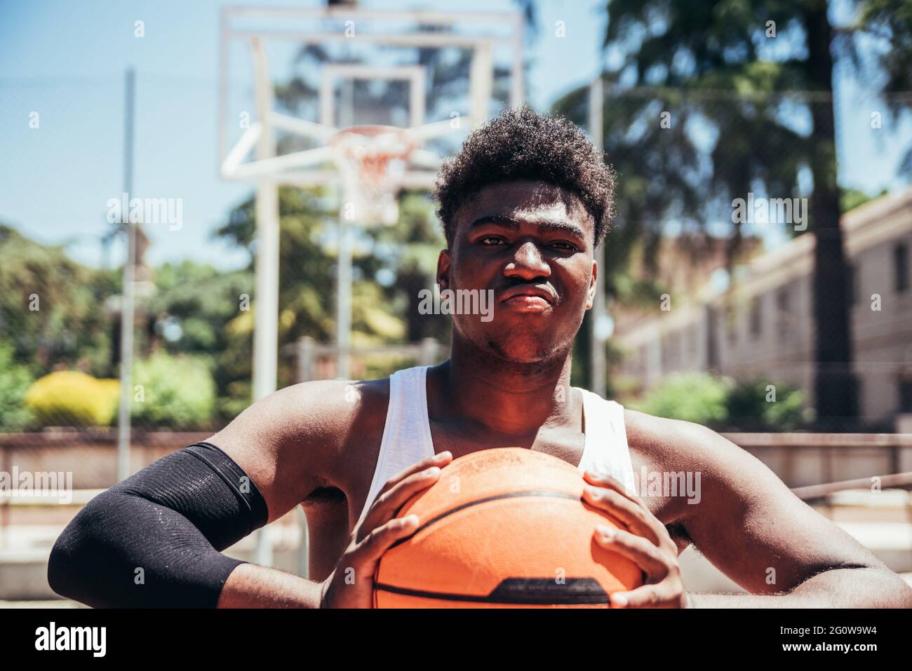 Portrait of a furious black Afro boy with a defiant look squeezing the basketball with his hands. Ready to play a game. Stock Photo