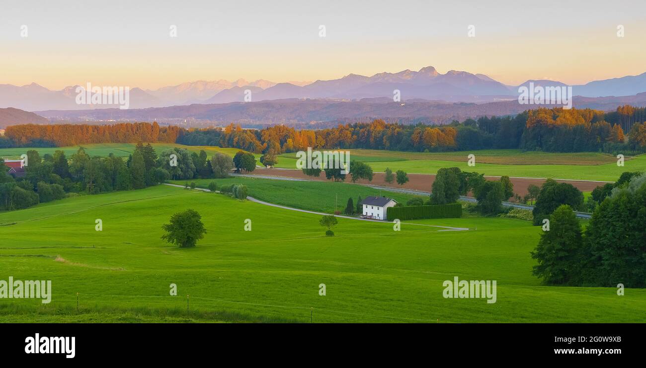 Wide panoramic view of the bavarian alps in germany with beautiful light during a summer sunset, as seen from Feldkirchen-Westerham, Bavaria. Stock Photo