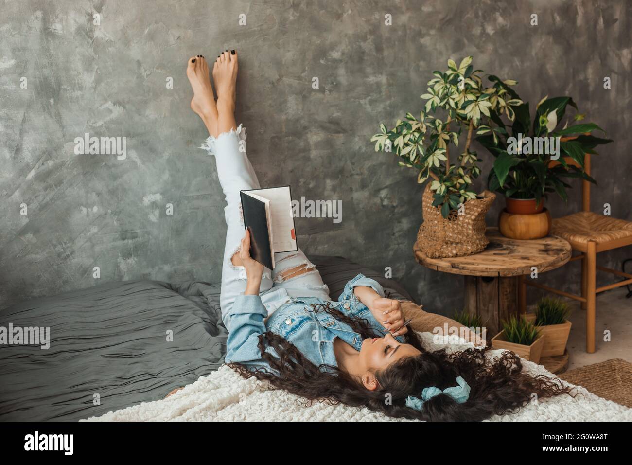 Brunette womancurly hair lies bed with crossed legs Stock Photo