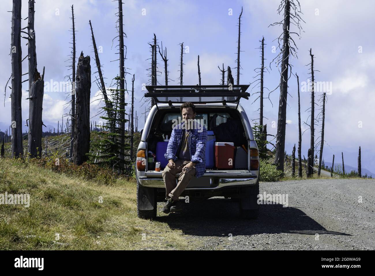 Male Sitting On Tailgate Smoking In The Mountains Stock Photo