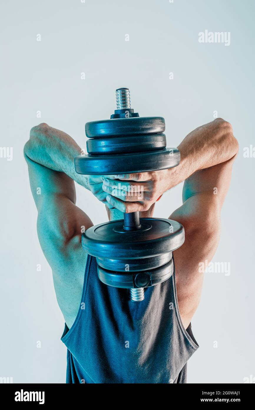 Young man training triceps muscles with dumbbell Stock Photo