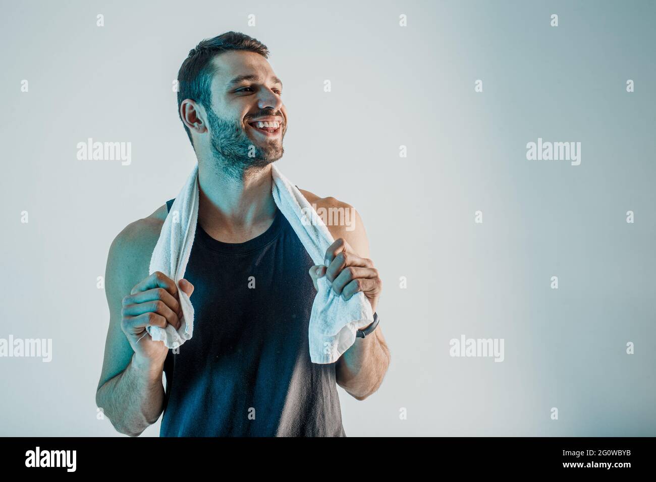 Smiling young sportsman with towel in studio Stock Photo