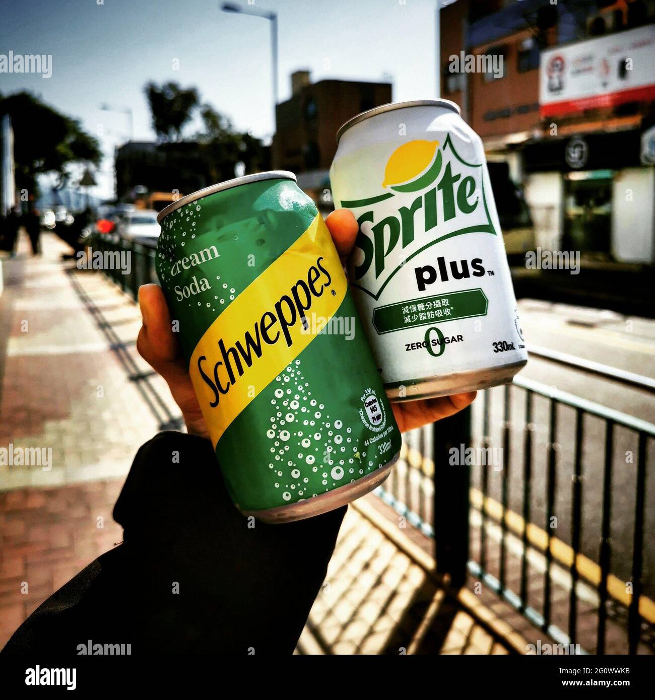 SAI KUNG, HONG KONG - Dec 10, 2019: A shot if a Schweppes cream soda can  and a Sprite Plus soda can being held up along the streets of Sai Kung, Hong