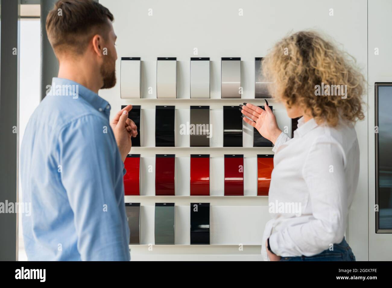 Saleswoman of the car dealership shows the customer samples of the