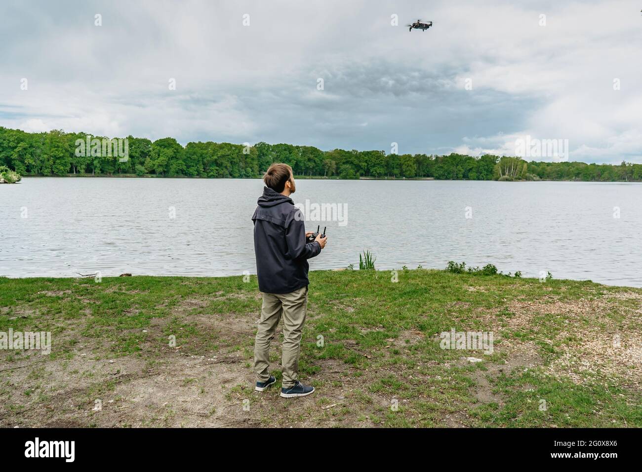 Man playing with drone for exam. Silhouette against fresh spring landscape.Male operating the drone by remote control and having fun. Pilot flying Stock Photo