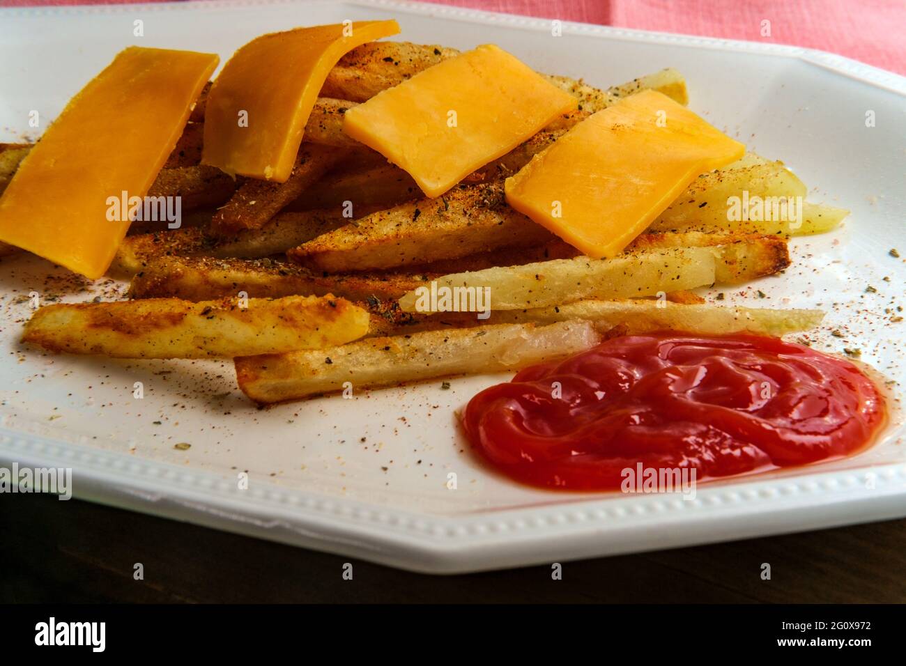 American French fried potatoes with cheese and seasoning Stock Photo
