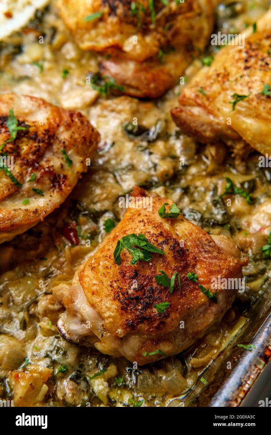 Crispy baked chicken thighs in a creamy spinach artichoke heart sauce