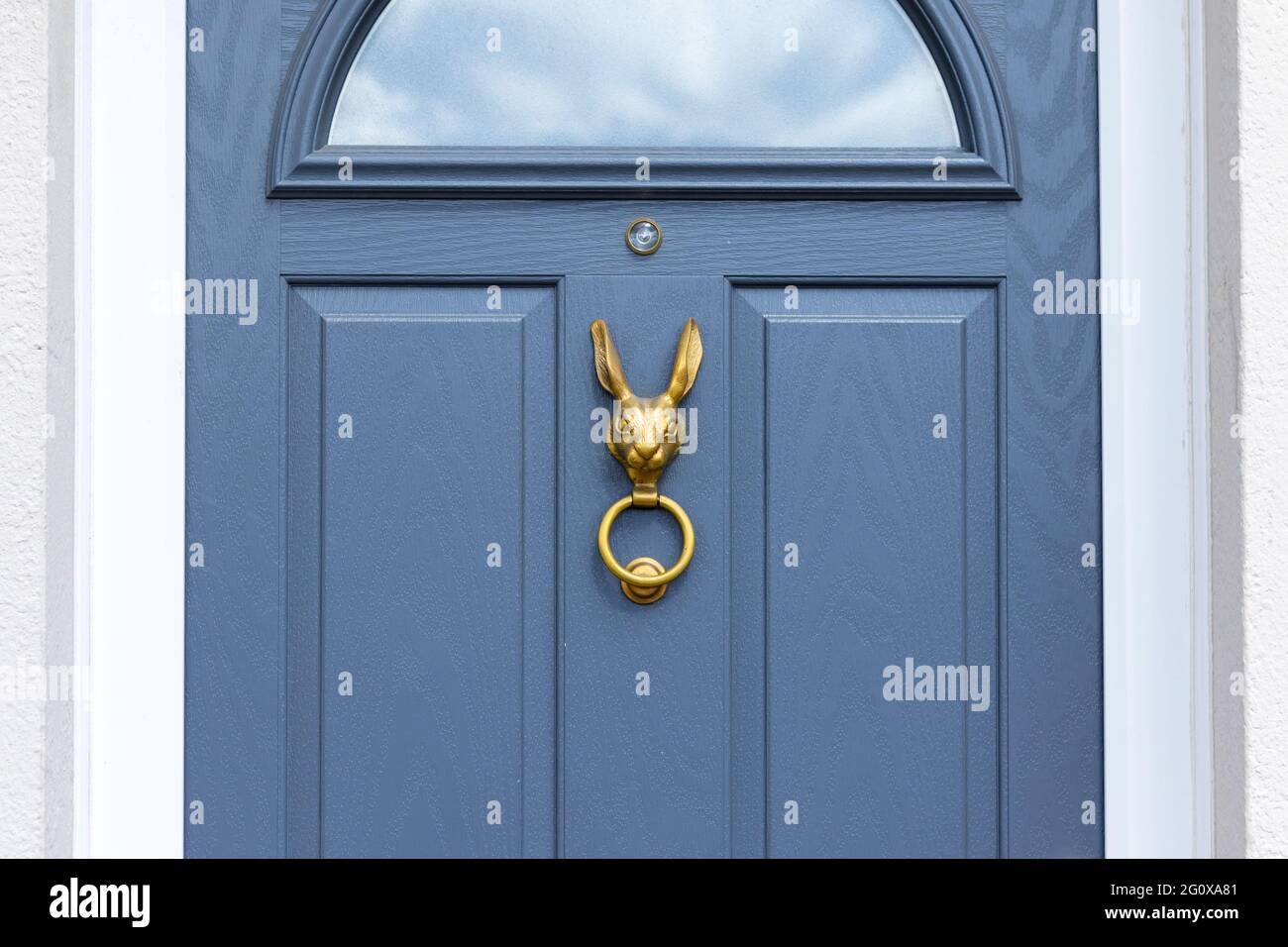 Blue wooden front door with bronze rabbit head door knocker holding a ring in its mouth Stock Photo