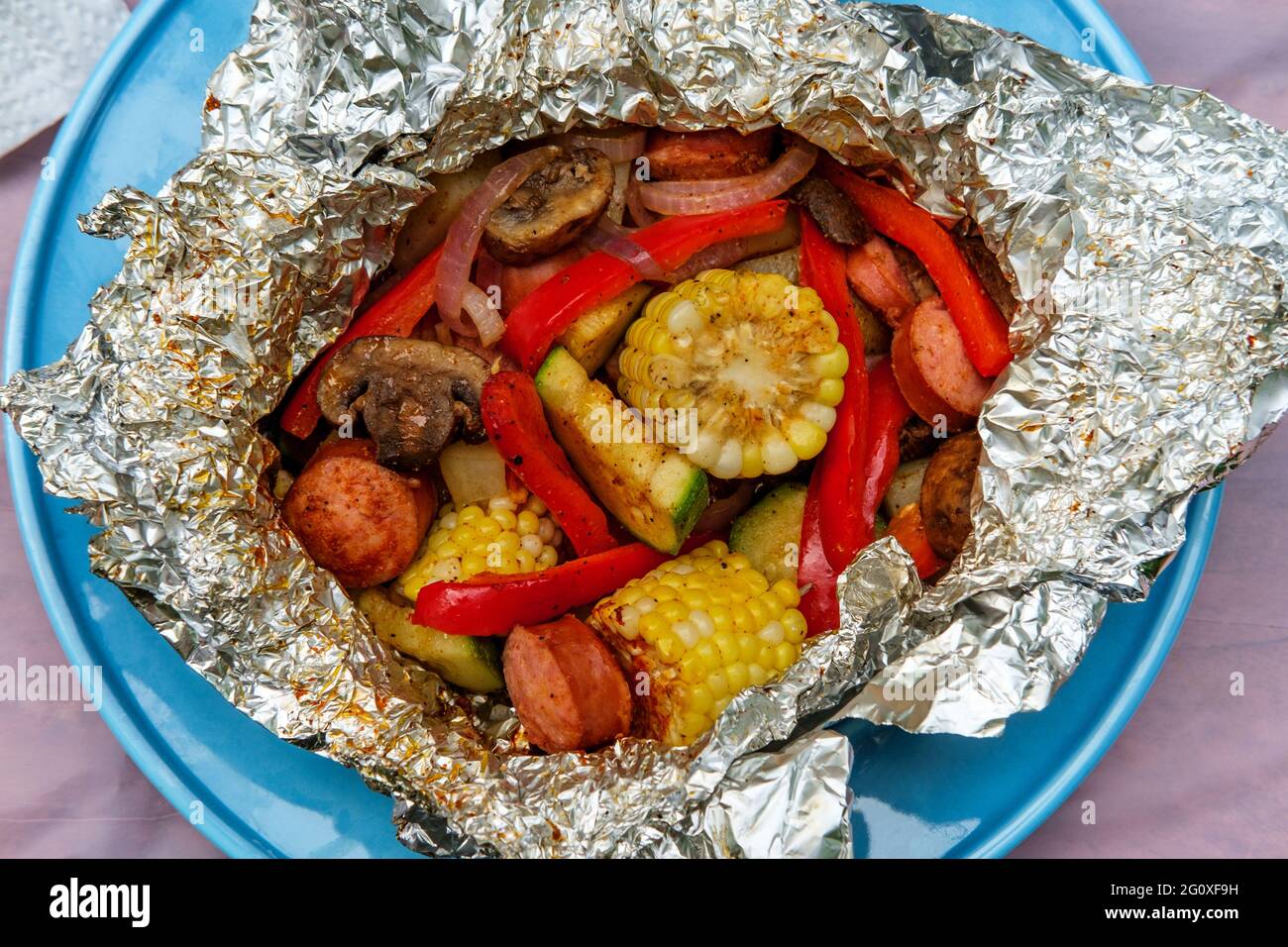 Grilled barbecue kielbasa foil packet with corn on the cob Stock Photo