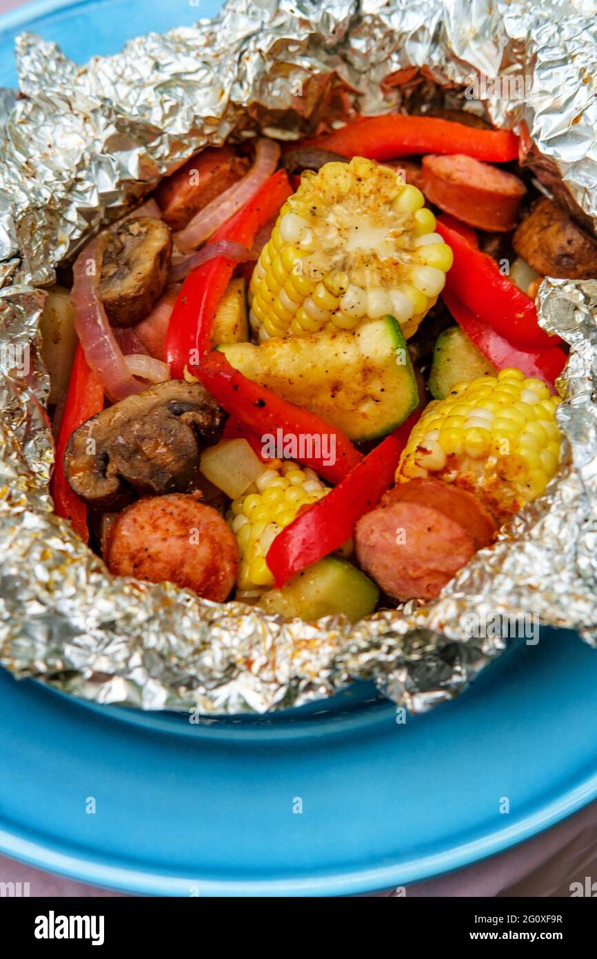 Grilled barbecue kielbasa foil packet with corn on the cob Stock Photo