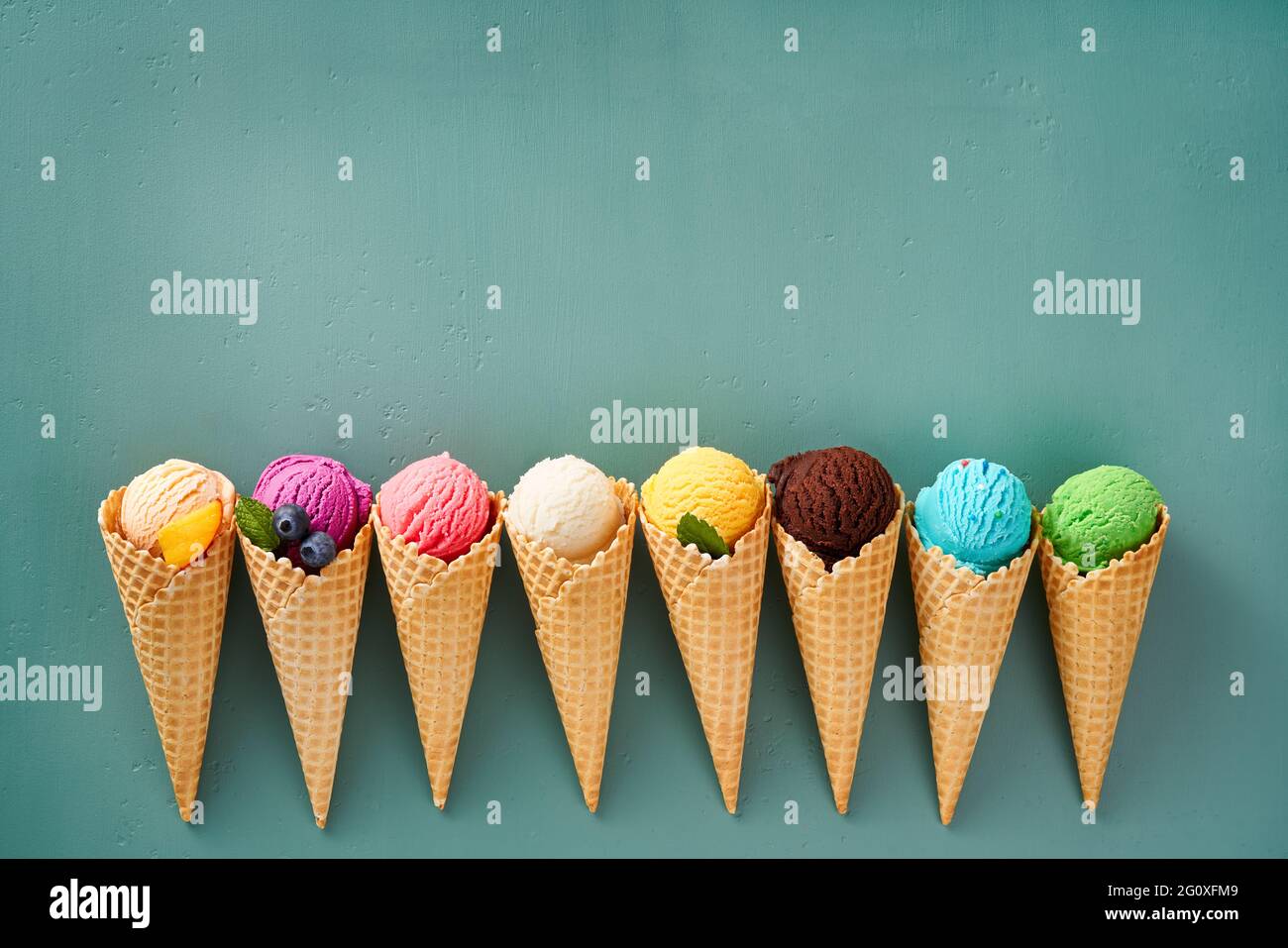 Assorted of ice cream in cones on blue background with copy space. Colorful set of ice cream of different flavours. Ice cream isolated with nuts, frui Stock Photo